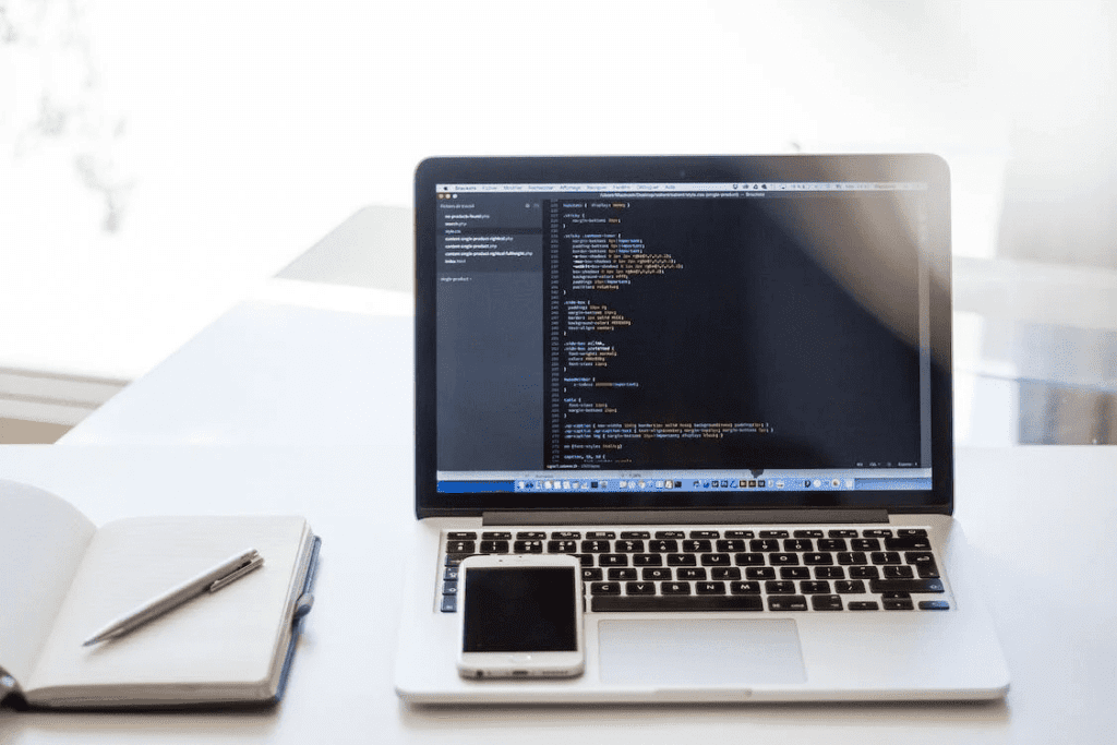 Create a Stunning Website using the WordPress HTML Editor Plugin. 2 A laptop with a notebook and phone, perfect for productive WordPress and HTML editing.
