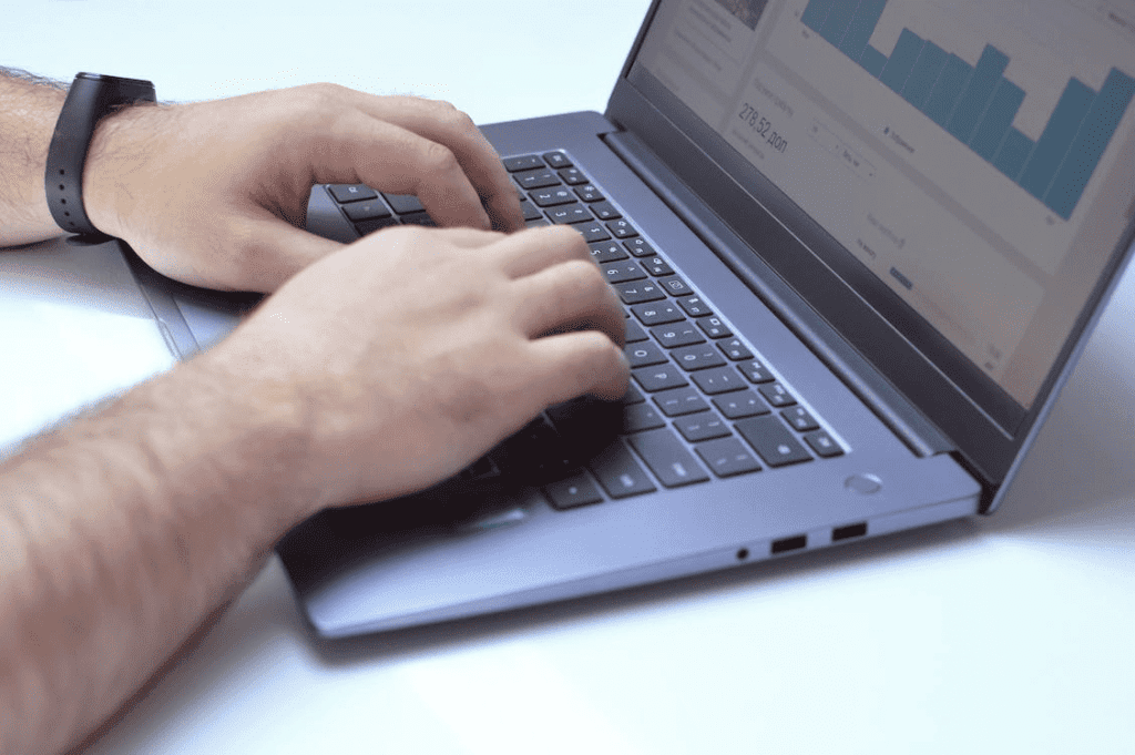 How to Use the Ahrefs WordPress Plugin to Analyze Your Site 3 A person typing on a laptop with a graph displayed on the screen and using the ahrefs plugin for WordPress.