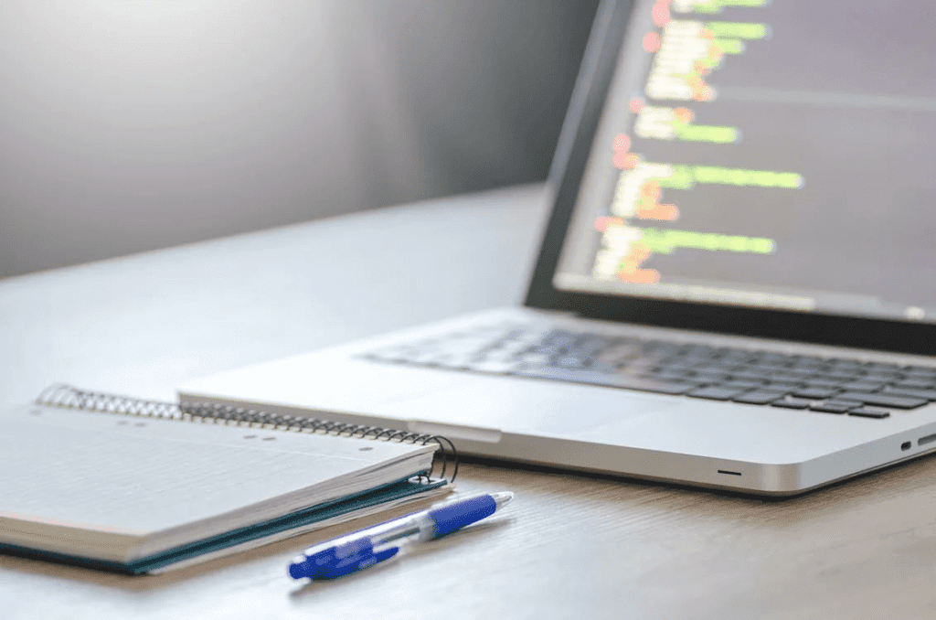 How Do You Clean WordPress Infection From an Existing Website? 4 A clean laptop is sitting on a table next to a notebook and pen.