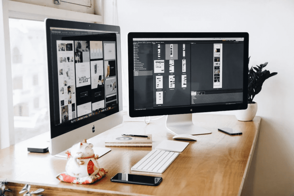 Two monitors on a desk next to a window, showcasing the use of some of the most common wordpress plugins.