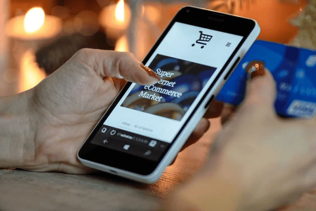 7 Essential Tips for Setting Up a WooCommerce for Service Business 3 A woman is using WooCommerce on her smartphone to make a payment with a credit card for a service business.